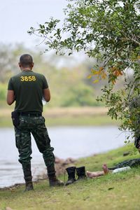 Rear view of army soldier standing at lakeshore