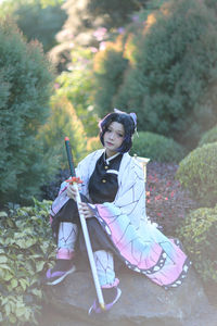 Full length of woman in costume sitting against plants