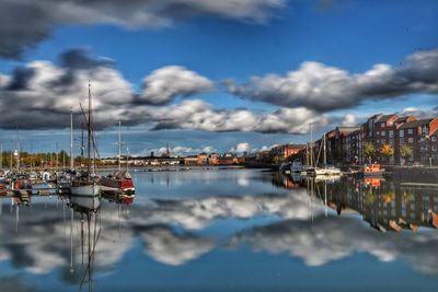 Sailboats moored at harbor against sky