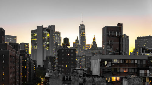 Illuminated buildings in city against sky during sunset