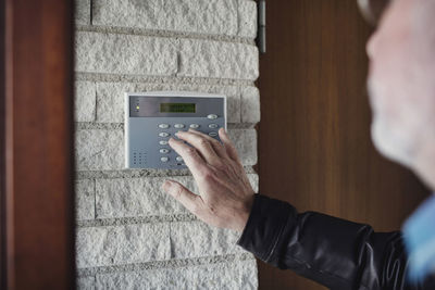 Cropped image of senior man using digital lock on white wall