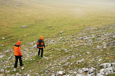 Rear view of people walking on field against sky