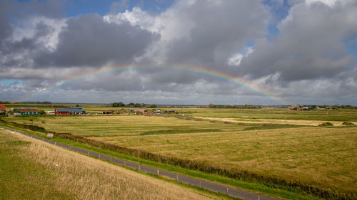 Scenic view of field against rainbow in sky