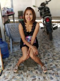 Portrait of smiling woman by parked motorcycle on seat