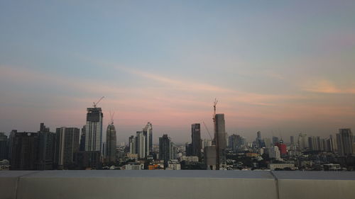 Modern buildings in city against sky during sunset