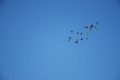 Low angle view of balloons against clear blue sky