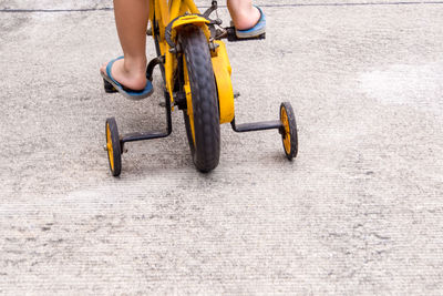 Low section of child riding bicycle on road