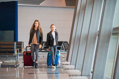 Sisters with suitcases walking in airport