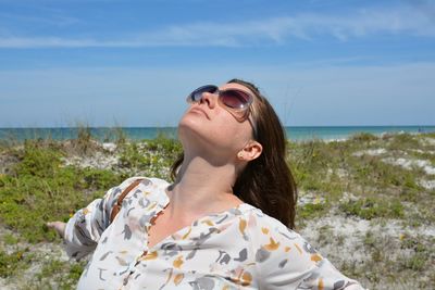 Beautiful young woman wearing sunglasses against sky