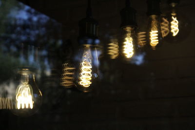 Low angle view of illuminated light bulbs hanging from ceiling