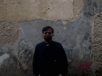 Portrait of young man standing against wall