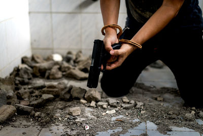 Midsection of man with handcuffs kneeling at home