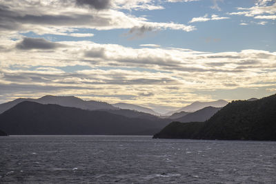 Scenic view of sea and mountains against cloudy sky