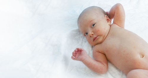 Close-up of baby boy lying on bed at home