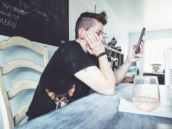 Side view of mature woman using phone on table