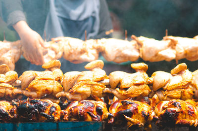 Close-up of person roasting chicken at barbecue grill