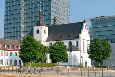 Old church and monastery st. heribert in front of a modern office building, cologne, germany