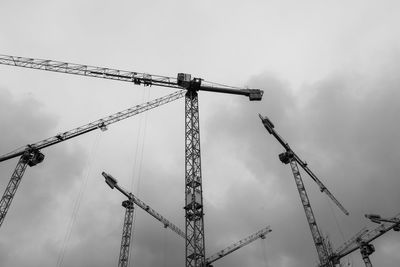 Low angle view of cranes at construction site against sky