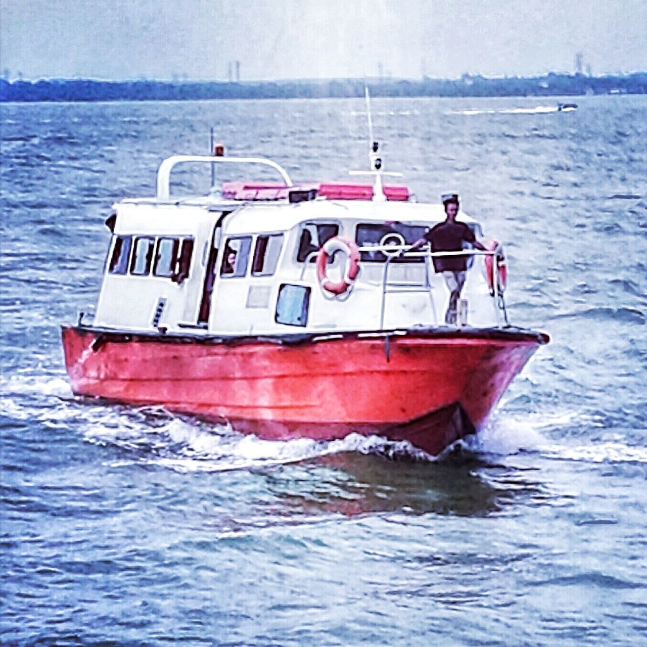 RED SHIP IN SEA AGAINST SKY