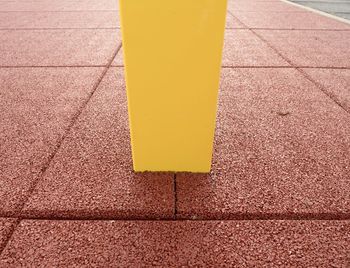 High angle view of yellow arrow symbol on sidewalk