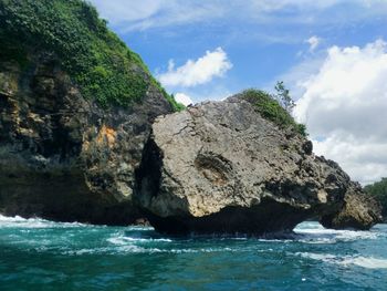 Rock formation by sea against sky