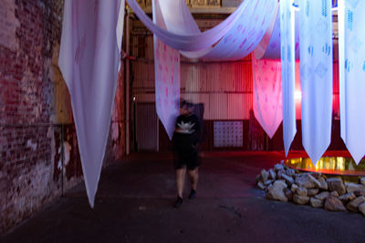 Full length of man standing at illuminated shop