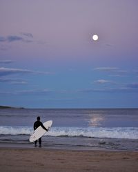 Rear view of man with surfboard on beach