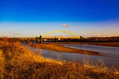 Bridge over river against sky during sunset