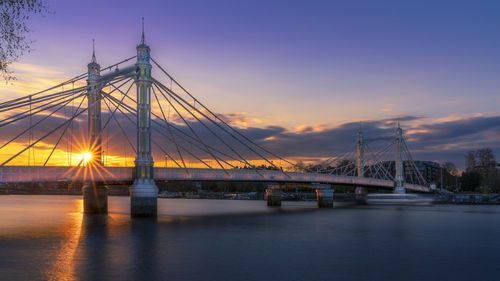 View of suspension bridge over river during sunset