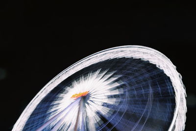 Close-up of illuminated ferris wheel against black background