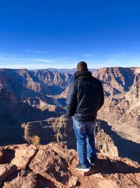 Rear view of man on rock looking at mountain