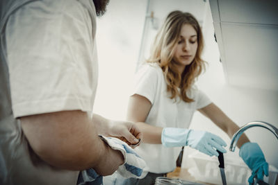 Couple cleaning utensils at sink