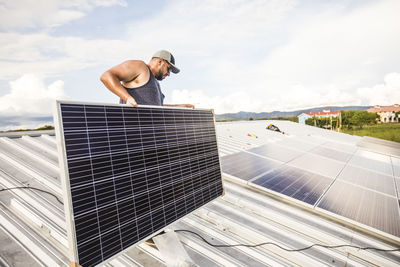 Electrician carries solar panel into place during installation.