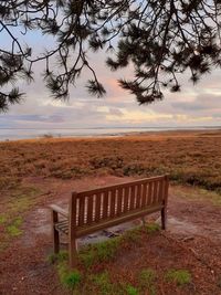 Bench on field against sky