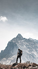 Rear view of man standing on mountain against sky