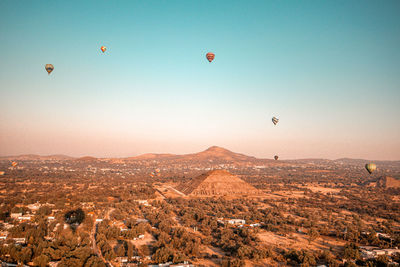 Hot air balloons flying over landscape against clear sky