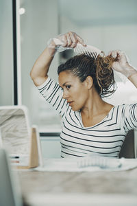 Rear view of young woman sitting on table