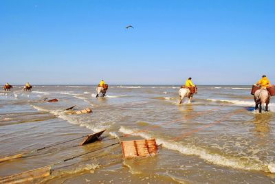 People on beach against clear sky