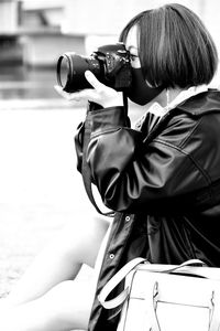 Side view of woman photographing outdoors