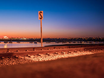 View of illuminated railroad tracks against sky during sunset