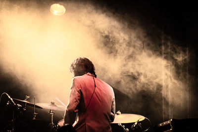 Rear view of a young woman music concert at night