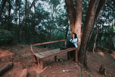 Man sitting on tree trunk in forest