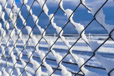 Full frame shot of chainlink fence against sky during winter