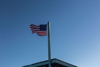 Low angle view of flag against clear blue sky