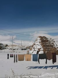 Clothes drying on snow covered field against sky