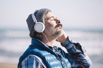 Caucasian man meditating on the beach with headphones in winter person