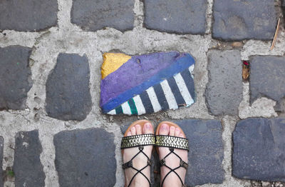 Low section of woman standing on cobblestone