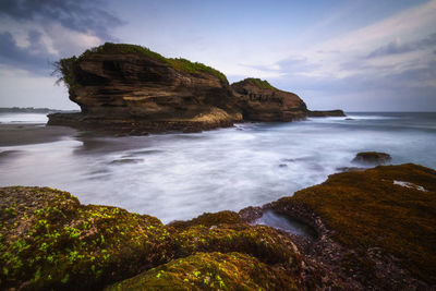 Rock formation on beach against sky