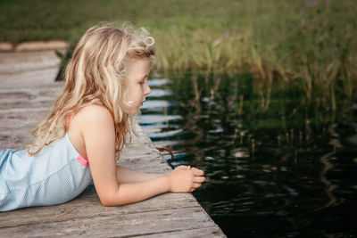 Cute girl lying down on pier by lake