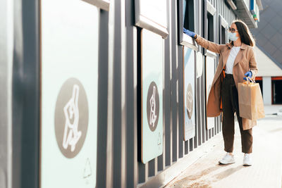 Woman standing by text on wall